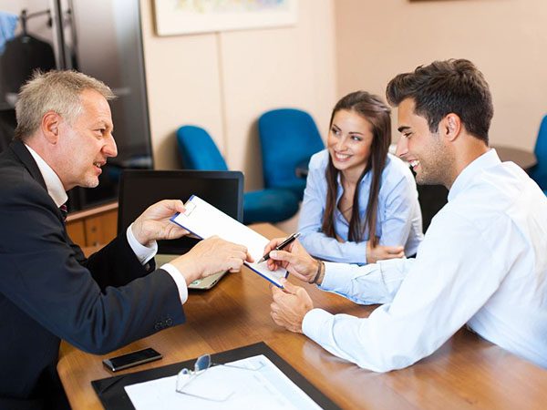 A man handing over papers to two people.